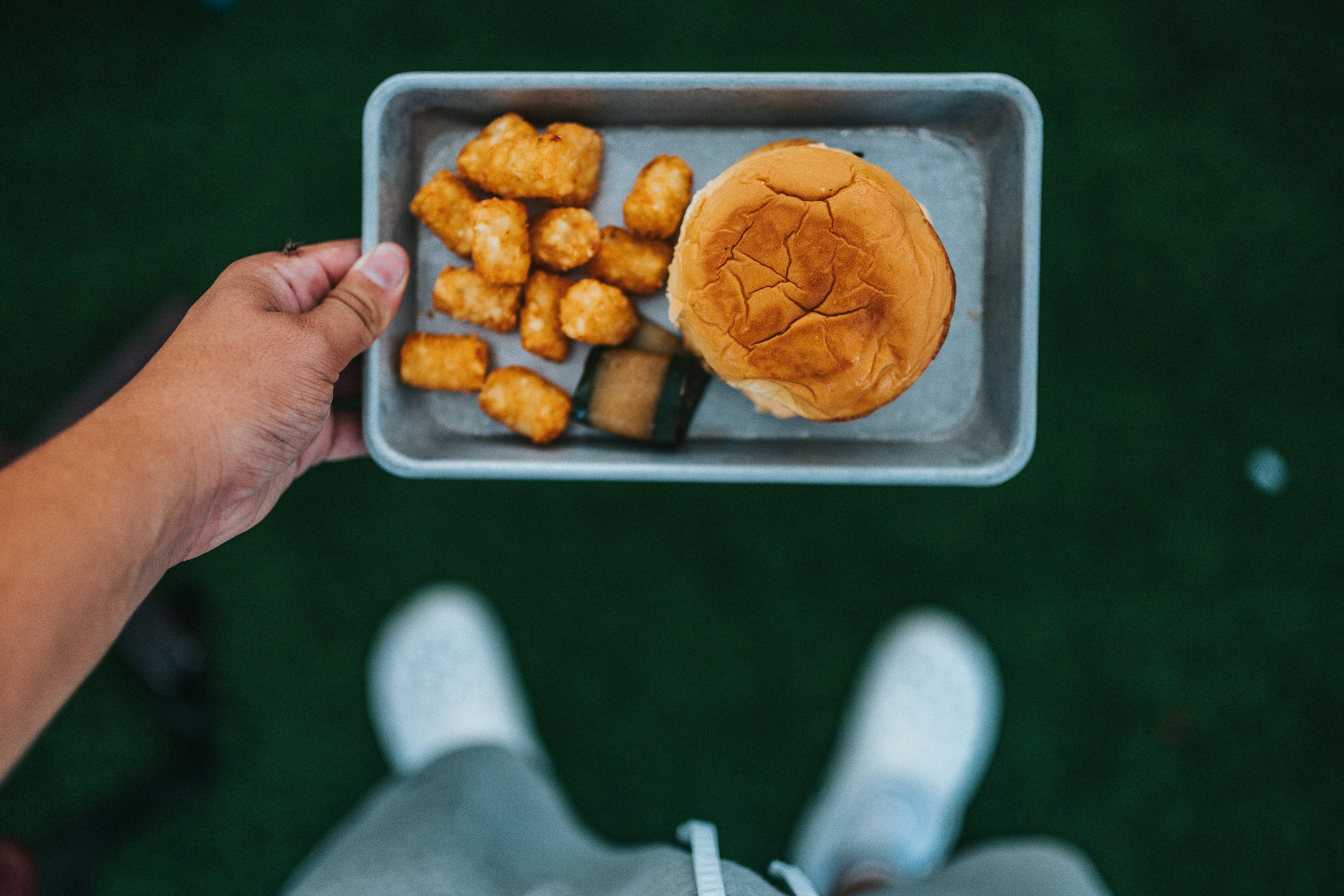 A simple plate with a burger and tater tots on it.